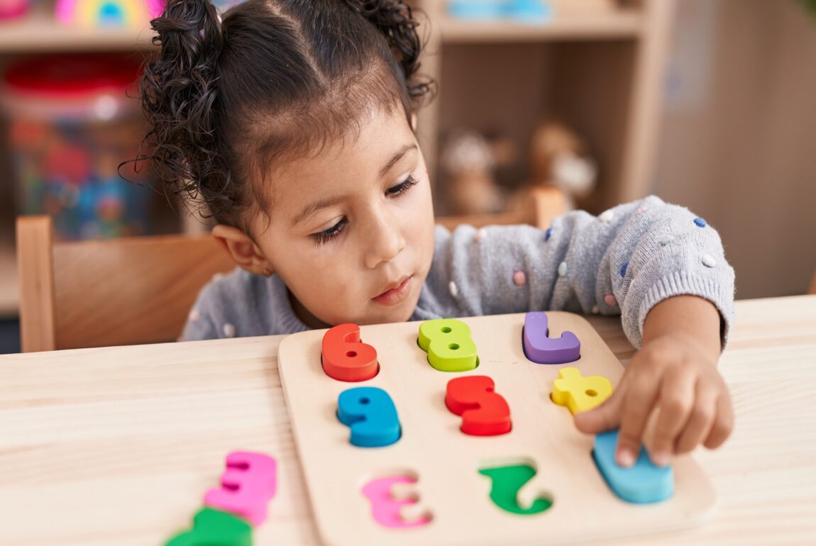 a preschool kid playing with maths puzzle game in a preschool