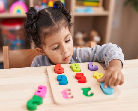 a preschool kid playing with maths puzzle game in a preschool