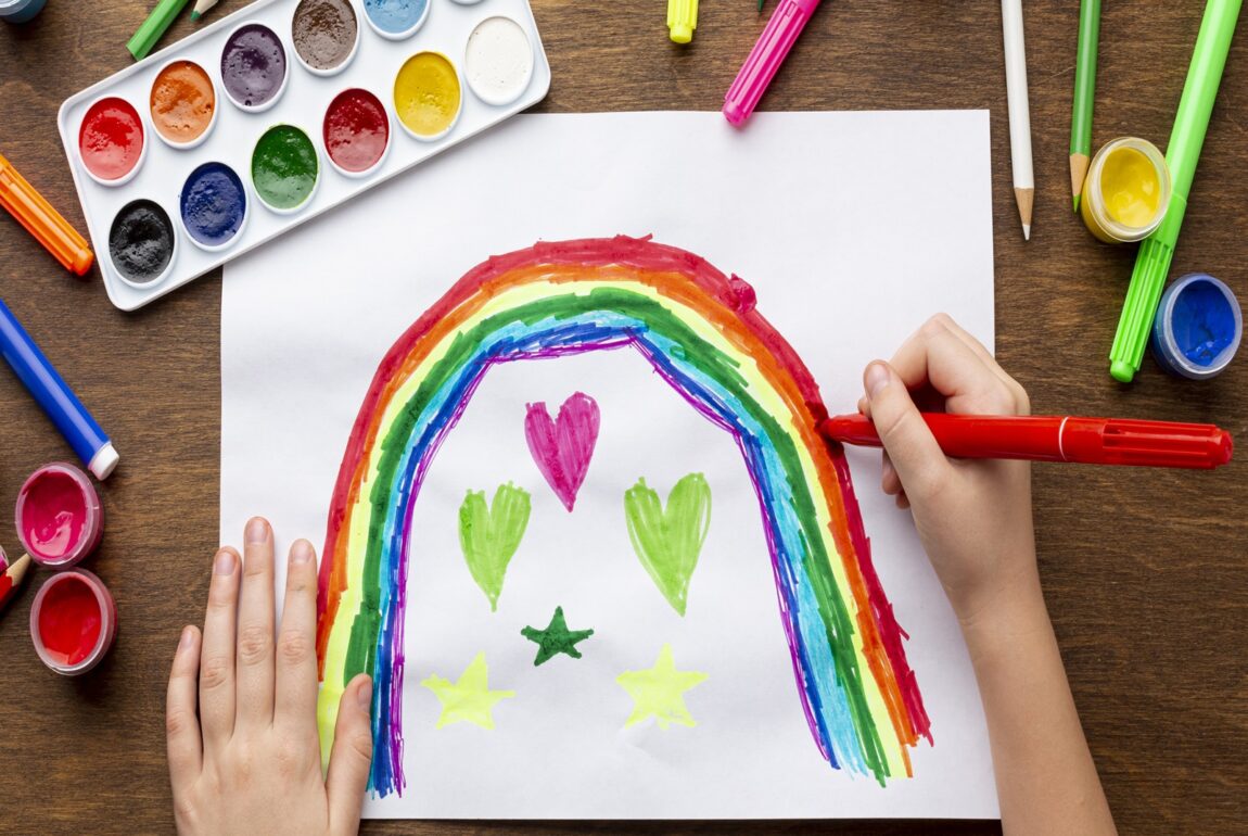 top-view-kid-drawing-rainbow-with-markers