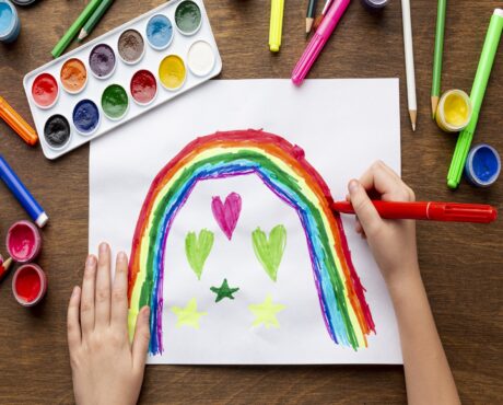 top-view-kid-drawing-rainbow-with-markers