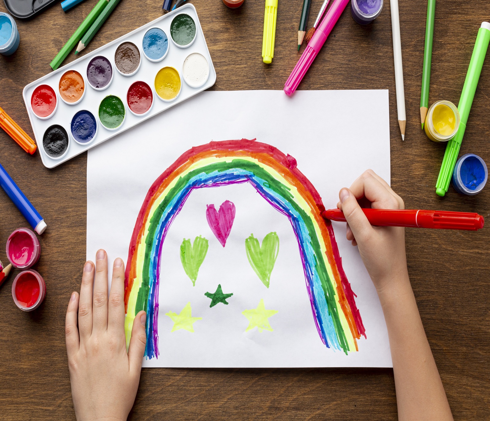 top-view-kid-drawing-rainbow-with-markers